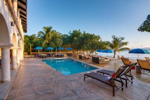 una piscina en un complejo con sillas y sombrillas en Mariposa Belize Beach Resort en Placencia Village