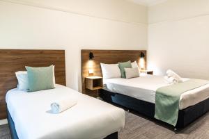 Dos camas en una habitación de hotel con blanco y verde en Salisbury Hotel Motel, en Brisbane