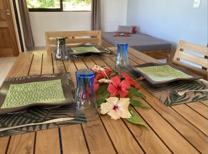 a wooden table with plates and vases and flowers on it at FARE ARIITEA in Bora Bora