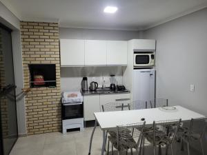 a kitchen with white cabinets and a table and chairs at Novo Lar Garopaba1 in Garopaba +5 photos