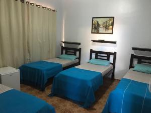 three beds in a room with blue and white at Recanto do Carreiro in Trindade