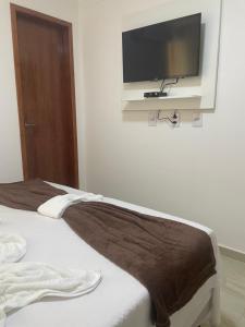 a bedroom with a bed with a flat screen tv on the wall at Maragobeach Suits in Maragogi