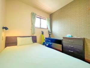 a bedroom with a bed and a dresser and a window at B&B 4 Rooms in Naha