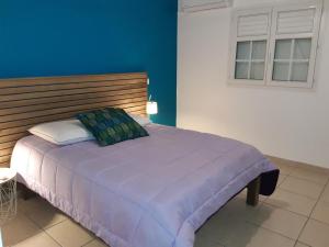 1 dormitorio con 1 cama grande de color púrpura y ventana en Villa Fleur de Lys en Sainte-Anne