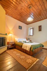 a bedroom with a bed and a wooden ceiling at Morfeas Guesthouse in Papingo