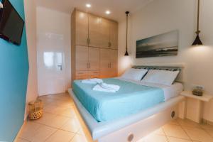 a bedroom with a large bed with blue sheets at Sagma calm apartment with amazing sea view in Perissa