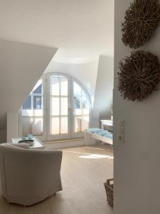 ein weißes Wohnzimmer mit einem Sofa und einem Fenster in der Unterkunft Ferienwohnung Schwalbe Wieck/Darss in Wieck