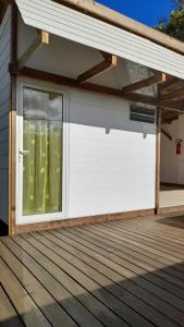 un garage blanc avec une fenêtre sur une terrasse dans l'établissement Mara'ai le spot Tubuai Chambre triple Taahueia Deluxe SDB privée avec piscine, à Tubuai