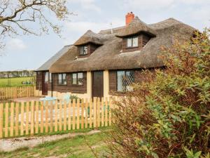 una vieja casa con techo de paja y una valla en Poppy Cottage en Tiverton