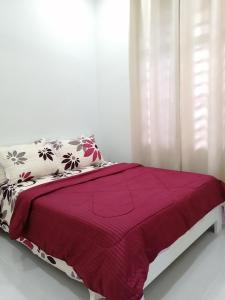 Simple Home by Aimie Fully Aircond في دونجون: سرير عليه بطانية ومخدات حمراء