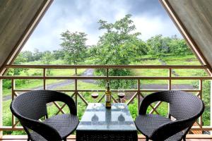 a table with two chairs and wine glasses on a balcony at StayVista at Wooden House with Jacuzzi in Wada