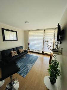 a living room with a black couch and a large window at Hermoso Departamento ubicado a 1 cuadra del lago Villarrica in Villarrica