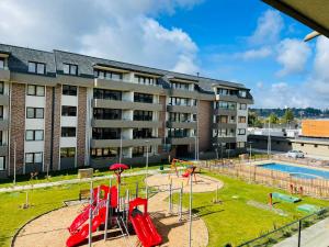 an apartment complex with a playground in front of a building at Hermoso Departamento ubicado a 1 cuadra del lago Villarrica in Villarrica