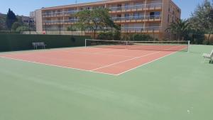 una pista de tenis frente a un edificio en MAZET DE LA MER 54M2 LAVANDOU 100M PLAGE avec PISCINE, en Le Lavandou