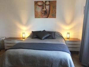 a bedroom with a bed with two tables and a painting at Black Cat Retreat holiday home in Nildottie