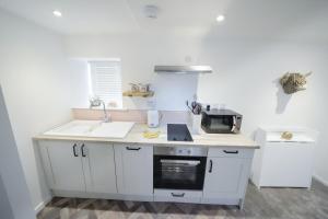 a white kitchen with a sink and a microwave at The Wee House by the Sea in Balintore