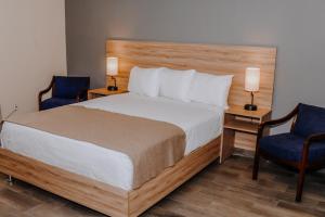 a bedroom with a bed and two blue chairs at Hotel Dunas Near Consulate in Ciudad Juárez