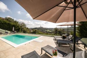 a swimming pool with chairs and an umbrella at Lange in Priocca