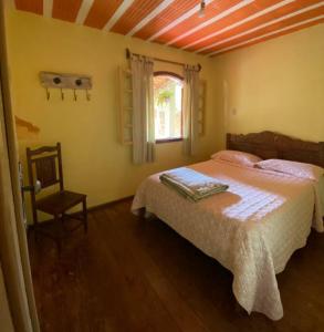 une chambre avec un lit, une chaise et une fenêtre dans l'établissement Casa das mandalas Lavras Novas, à Lavras Novas