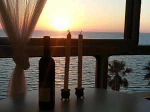 a bottle of wine and two candles on a table in front of a window at Magic on the sea-suites with a private jacuzzi and a private sea view in Netanya