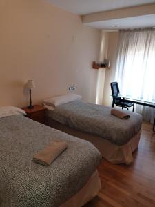 a room with two beds and a chair and a window at Quintanar Jaca in Jaca