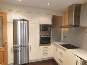 a kitchen with white cabinets and a stainless steel refrigerator at Quintanar Jaca in Jaca