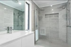 a white bathroom with a shower and a sink at Luxurious 5 bedroom Villa with hot tub & much more in Rosebud