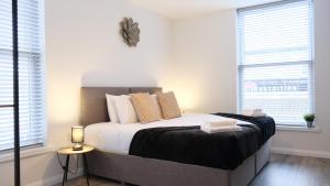 a bedroom with a large bed with two windows at Leisure & Contractors - Stylish Town Centre Apartment with Free Parking in Bedford