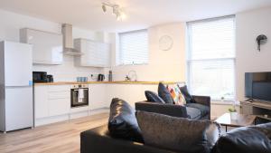 a living room with two couches and a kitchen at Leisure & Contractors - Stylish Town Centre Apartment with Free Parking in Bedford
