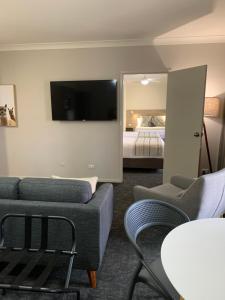 uma sala de estar com um sofá, uma televisão e uma cama em Hamilton Henry Parkes Motor Inn em Parkes