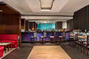 a restaurant with a bar with stools and a red couch at Ramada by Wyndham Jaipur North in Jaipur