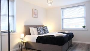 ein Schlafzimmer mit einem Bett und zwei Fenstern in der Unterkunft Modern Contractors & Family Apartment - Central Location inc Private Parking in Bedford