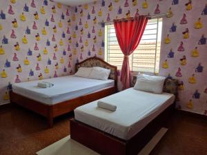 two beds in a room with a wall with dolls at Soben Sensok Guesthouse in Phnom Penh