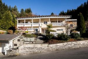 a large white house with a stone wall at Villa am First in Oberstdorf