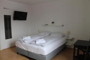 Bett in einem Zimmer mit einem TV an der Wand in der Unterkunft Boardinghouse Georgsheil in Südbrookmerland