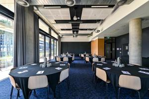 Nesuto Curtin Perth Hotel في بيرث: قاعة اجتماعات فيها طاولات وكراسي