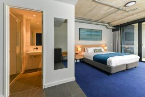 a bedroom with a bed and a bathroom at Nesuto Curtin Perth Hotel in Perth