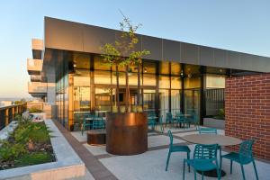 a building with a table and chairs and a tree at Nesuto Curtin Perth Hotel in Perth