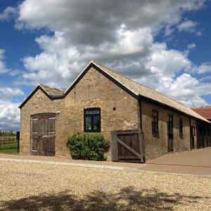 un antiguo edificio de ladrillo con dos puertas y una ventana en The Yard @ Pringle Farm en Great Stukeley