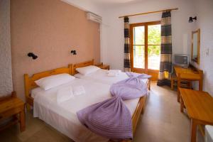a bedroom with a large bed with a purple blanket on it at Marie Hotel in Acharavi