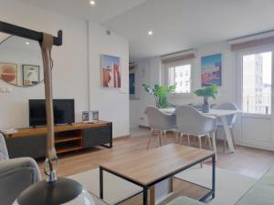 een woonkamer met een tafel en stoelen en een televisie bij Apartamentos Rey by Como en Casa in Santiago de Compostela