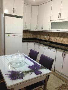 a kitchen with white cabinets and a table with flowers on it at Kapukargın apart villa in Dalaman