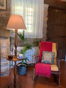 una lámpara sentada junto a una silla roja junto a una mesa en La Casita de Cuestallano, en Renedo