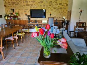 a dining room with a table with flowers in a vase at Ferme de Tayac - Charme avec Pool in Les Eyzies-de-Tayac