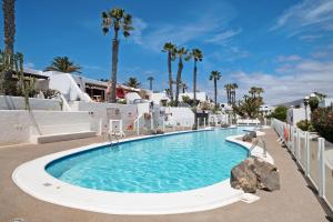 a large swimming pool in a resort with palm trees at Puerto Chico W in Playa Blanca