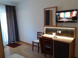 a room with a tv and a desk with a chair at Pensiunea Stefania in Lacu Rosu