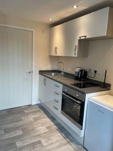 een keuken met een wastafel en een fornuis top oven bij Lovely 1 bedroom studio apartment - Merthyr Tydfil in Merthyr Tydfil