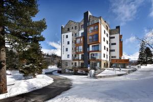 a large building in the snow with snow covered ground at APLEND Hotel Ovruč in Vysoke Tatry - Strbske Pleso