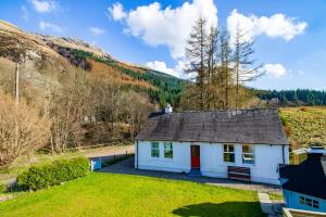 una piccola casa bianca in mezzo a un campo di Lagnaha Cottage a Kentallen