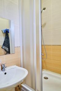 een badkamer met een wastafel en een douche met een spiegel bij Троицкая люккс апартамены посуточно почасово in Sumy